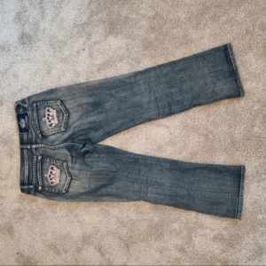 Victoria Beckham x Rock & Republic - Säljer mina Jättefina jeans med raka ben från Victoria Beckham x Rock & Republic. Jeansen är blåa med rosa kronor på fikorna och små silvriga stenar. Tyvärr saknas några stenar men inget man märker. Måtten står på sista sidan och är i cm !💗(Köpte de här men jag har nästan aldrig använt de) skriv om ni har frågor! OBS.Jag vet inte exakta storleken men jag har S i de flesta kläderna och jeansen är lite för stora på mig! 