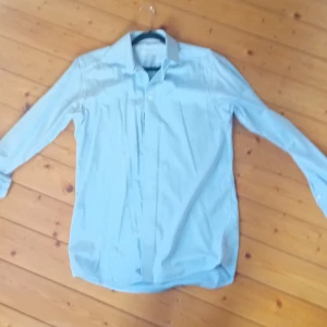 Ljusblå skjorta från Eton - Säljer en stilren ljusblå skjorta från Eton i modellen Contemporary. Skjortan har klassisk krage, långa ärmar och diskreta röda detaljer på insidan av kragen. Perfekt för dig som gillar en clean och dressad look.