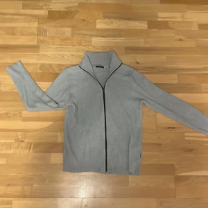 Full Zip up - Grå Zip up från jack and Jones. Står storlek XL men passar L mycket bättre. Använd några gånger, väldigt fint skick. Nypris ca 799kr, mitt pris 249kr