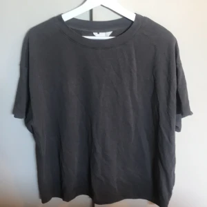 Mörkgrå t-shirt - En basic mörkgrå t-shirt med rund halsringning och avslappnad passform. Perfekt att matcha med jeans eller shorts för en enkel och stilren look.