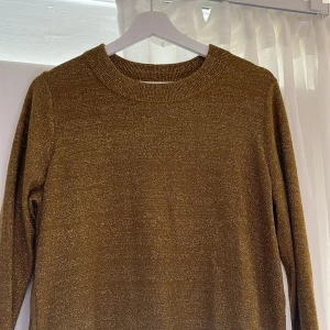 Guldig stickad tröja med dragkedjor - Säljer en snygg guldig stickad tröja med glittrig finish i storlek M. Tröjan har långa ärmar och coola dragkedjor längs sidorna. Jag säljer denna för 89 kr + frakt. 