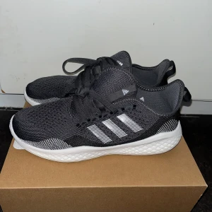 Svarta Adidas sneakers med vita ränder - Snygga svarta Adidas sneakers med klassiska vita ränder på sidan och vit platt sula.Perfekta för vardagsbruk eller träning. Stl 40 2/3