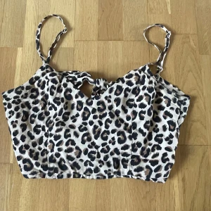 Leopardmönstrad croppad linnetopp från H&M Divided - Säljer en croppad linnetopp från H&M Divided med leopardmönster. Toppen har smala axelband och knytning i ryggen. Perfekt för dig som gillar leopardmönster och vill ha en trendig look.