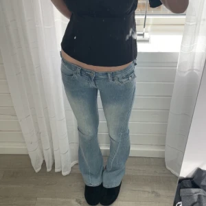 True Religion Joey Low Rise Flare jeans - Säljer ett par ljusblå True Religion  jeans Joey med jätte låg midja och utsvängda ben. Detaljer i form av silverfärgade knappar på fickorna där bak. Snygg passform och vintagekänsla. Liten extraficka med knapp fram 