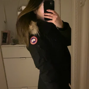 Svart parkajacka från Canada Goose med pälskrage - Säljer min äkta Canada Goose Trillium Parka i dammodell, storlek XS och färg svart. Jackan är varm, snygg och perfekt för kalla vintrar. Den är i fint skick och sparsamt använd – men har lite noppor/slitage på ena ärmmudden (se bild), vilket är inräknat i priset. 	•	Äkta päls (avtagbar) 	•	Flera praktiska fickor 	•	Figursydd och stilren modell 	•	Made in Canada, modell 2530L  Nypris ca 13 500 kr – mitt pris: 4300 kr (kan diskuteras vid snabb affär.)