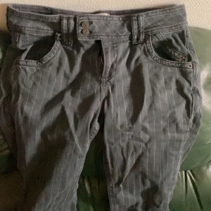 Gråa randiga jeansbyxor från BDG/ urban outfitters  - Gråa jeansbyxor från BDG med tunna vita ränder. Klassisk femficksmodell med bälteshällor och dubbla knappar i midjan. Snygg och enkel design som passar till mycket.