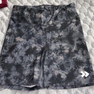 Svarta och grå träningsshorts med batikmönster från 15% - Snygga träningsshorts i svart och grått batikmönster från 15%. De har en normal passform och är tillverkade i ett stretchigt syntetmaterial. Perfekta för gymmet eller löprundan.