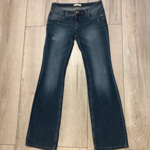 Blå bootcut jeans från Clockhouse - Snygga blå bootcut jeans från Clockhouse med klassisk femficksdesign och normal passform. Jeansen har låg midja och subtila slitningar framtill för en avslappnad look. Perfekta till sneakers eller boots.