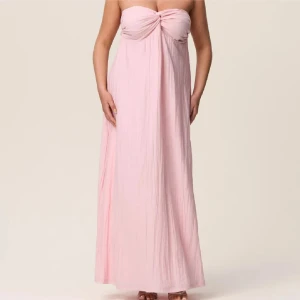 Ljusrosa långklänning från Adoore - Supersöt ljusrosa långklänning från Adoore med axelbandslös design och en snygg rosettliknande detalj vid bysten. Klänningen har en luftig och flowy passform. Använd 3 gånger