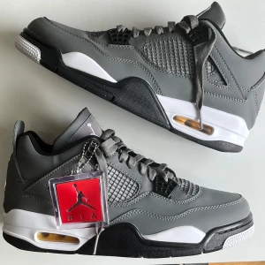 Nike Air Jordan 4 Retro Cool Grey - HELT NY Snygga Nike Air Jordan 4 Retro i färgen Cool Grey med grått skinn, svarta och vita detaljer samt gula accenter på sulan. Klassisk siluett med meshpaneler, snörning och Jumpman-logga på baksidan. Perfekta sneakers för dig som gillar streetwear.