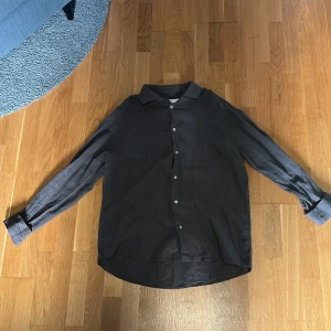 Mörkgrön skjorta med knappar - Stilren mörkgrön skjorta med klassisk krage och vita knappar framtill. Skjortan har lång ärm och är tillverkad i ett tunt, mjukt tyg som ger en avslappnad känsla. Perfekt för dig som gillar en enkel men snygg look.