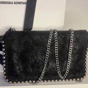 Axelväska från Zara - Snygg svart axelväska , silverfärgad kedja och pärlor längs kanterna. Väskan har flera fack med dragkedja och en bred axelrem. Perfekt för att liva upp en outfit nu till sommarn💕