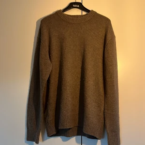 Brun stickad tröja från H&M - Brun stickad tröja från H&M i relaxed fit. Tröjan har rund halsringning och långa ärmar med ribbade muddar vid ärmslut och nederkant. Perfekt för kyligare dagar. Aldrig använd.