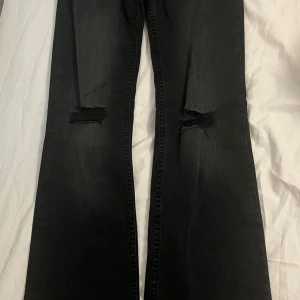 Svarta bootcut jeans med hål på knäna - Svarta jeans med bootcut passform och hål på båda knäna. Säljer då dom inte passa, dom är i helt nytt skick 