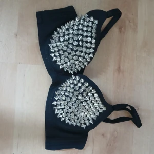 Nitt bh Svart bh med nitar - Nitt bh Cool svart bh med massor av silvriga nitar på kuporna. Perfekt för dig som vill sticka ut och ge din outfit en edgy touch. Bh:n har justerbara axelband och en klassisk passform.