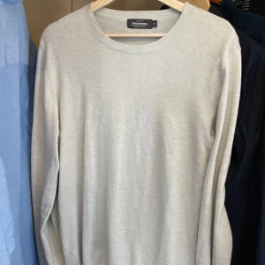 Ljusgrå stickad tröja  - En stilren ljusgrå tröja med rund halsringning och långa ärmar. Perfekt för lager-på-lager och enkel att matcha med olika outfits. Mjuk och bekväm känsla.