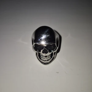 Dödskalle Ring! - En sjukt fet Dödskalle ring! Köpt i höstas på Punkt Shop i Stockholm. Nästan nyskick utom lite repor som syns med blixt samt nåt märke på baksidan och i ena ögat. Materialet är stål så jag antar att det är rostfritt 😁 Skriv för frågor eller kika min profil för eventuella bundles :) Köpt för 99:-