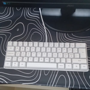 Vit mekanisk tangentbord med RGB-belysning - Säljer ett kompakt vitt mekaniskt tangentbord med RGB-belysning. Tangentbordet har ett minimalistiskt 60%-layout och tydliga tecken på tangenterna. Perfekt för gaming eller skrivbordsarbete där du vill ha färgglad belysning.