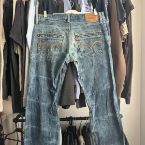 Levi's 527 bootcut jeans blå - Säljer ett par klassiska Levi's 527 jeans i blå tvätt med bootcut-passform. Jeansen har snygga slitningar, fem fickor och ikoniska Levi's-detaljer på bakfickorna. Perfekta för dig som gillar en lite vidare stil nertill.