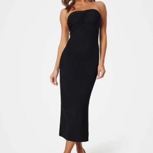 Svart axelbandslös långklänning - Säljer en svart axelbandslös långklänning med figurnära passform. Klänningen har en enkel och stilren design som ger en elegant siluett. Perfekt för dig som vill ha en klassisk look med modern twist.