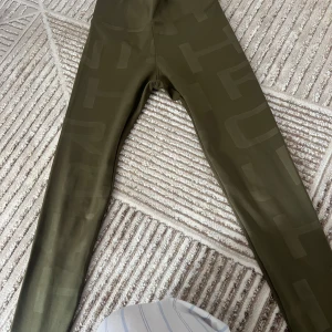 Olivgröna tights från Röhnisch - Snygga olivgröna tights från Röhnisch med diskret mönster och hög midja. Perfekta för träning och har en tight passform som sitter bekvämt. Materialet är stretchigt och känns mjukt mot huden.