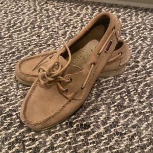Sebago dockside’s beige  - Säljer ett par klassiska beige loafers i mocka från Sebago. Skorna har snörning runt om, rund tå och platt sula. Perfekta för en avslappnad och stilren look. Använda ett fåtal ggr. Ifall ni vill ställa fler frågor är det bara att skicka dem!