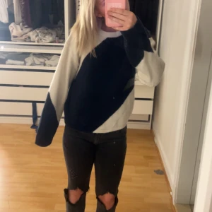Svart och vit stickad tröja - Säljer en snygg stickad tröja i svart och vitt med coolt diagonal färgblocksmönster. Tröjan har långa ärmar och en avslappnad passform, perfekt till jeans eller kjol. Superenkel att styla för en trendig look! Den är från ginas barn av delning i storlek 170 men passar både xs/s