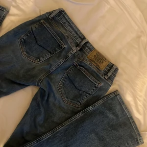 Blå jeans från Rock & Republic - Snygga blå jeans från Rock & Republic med klassisk femficksdesign och knappgylf. Perfekta för en avslappnad stil. 