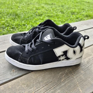 Svarta sneakers från DC Shoes - Skorna passar mig som har 38/39 i skostorlek. Svarta sneakers från DC Shoes med vit logga på sidan och vit sula. Klassisk skatemodell med rund tå och platt sula, perfekt för en avslappnad streetstil. 