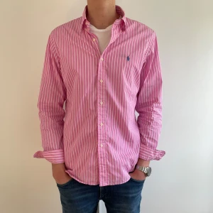  Randig skjorta från Polo Ralph Lauren - Tjena! Säljer en rosa och vit randig skjorta från Polo Ralph Lauren i slim fit-modell. Tröjan är i storlek L och är mycket stilren, perfekt inför sommaren! 🏖️Tröjan är i riktigt fint skick! Tveka inte på att skriva om du har frågor eller funderingar!🙌 Priset är inte hugget i sten 🪨 