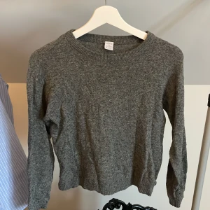 Grå stickad tröja från Lindex - Mysig grå stickad tröja från Lindex med rund halsringning och långa ärmar. Perfekt för kyligare dagar och enkel att matcha med olika outfits. Klassisk modell med ribbade muddar vid ärmslut och nederkant. Använd men utom lite nopprig så är det inga problem💞
