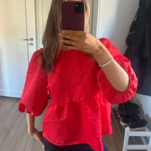 Röd blus med puffärmar - Säljer en röd blus med trekvarts puffärmar och rund halsringning. Blusen har en lös passform och är tillverkad i ett lätt, strukturerat tyg. Bara Andvänd en gång, så mycket fin. 