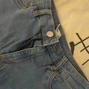 Blå jeansbyxor med dragkedja - Säljer ett par klassiska blå jeansbyxor med dragkedja och knapp framtill. Byxorna har bälteshällor och synliga sömmar i kontrastfärg. Perfekta till vardags och enkla att matcha med olika toppar.