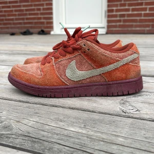 Nike SB Dunk Low i mocka - Säljer ett par Nike SB Dunk Low med röd mocka och lila sula. 