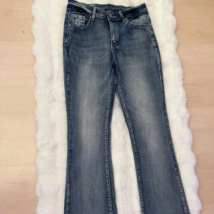 Blå bootcut jeans från SHEIN med dekorerade bakfickor - Säljer ett par blå bootcut jeans från SHEIN i storlek S. Jeansen har snygga dekorationer på bakfickorna och klassisk femficksdesign. Perfekta för dig som gillar en lite utsvängd passform och vill ha något extra på detaljerna. En av knapparna på fickan är borta som man kan se på bilden.