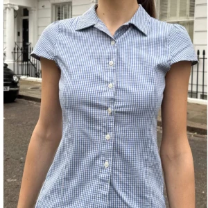 Blårutig kortärmad skjorta - Säljer en söt blårutig skjorta med korta ärmar från Brandy Melville .  Nyskick, Använd en gång. Passar som xs/s . Original pris : 340kr 