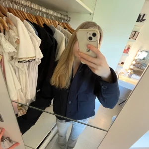Marin blå kappa från H&M - Säljer en marin blå kappa från H&M med stora fickor framtill och knäppning med knappar. Jackan har en rak passform och är långärmad. Perfekt att styla till jeans eller kjol för en trendig look. Aldrig använd och är därav i ny skick fast utan prislapp. 