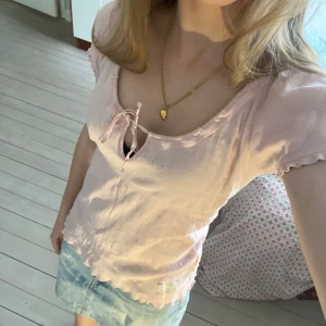 Ljusrosa topp från Odd Molly - Supersöt rosa topp/blus från Odd Molly med rosett framtill och vågig kant nertill. Toppen har korta ärmar och är tillverkad i mjukt bomullsmaterial. Perfekt för vår och sommar! Köpt second hand men inga tecken på användning eller defekter. 