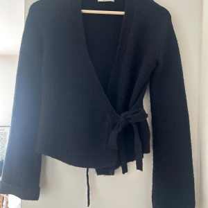 Svart omlottkofta med knytband - Säljer en svart omlottkofta med långa ärmar och knytband i midjan. 