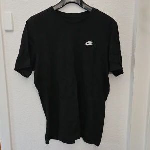 Svart t-shirt från Nike - Säljer en svart t-shirt från Nike med liten vit logga på bröstet. Klassisk rund hals och korta ärmar. Perfekt för en sportig och avslappnad stil.