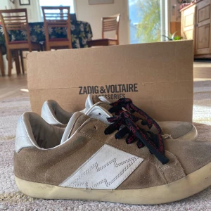 Beige sneakers från Zadig & Voltaire  - Säljer ett par beige sneakers från Zadig & Voltaire i mocka och läder. Hyfsat bra skick och box kommer med! Obs defekt på sulan!