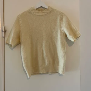 Beige stickad kortärmad tröja från DAY - Säljer en beige stickad tröja från DAY Birger et Mikkelsen. Tröjan har korta ärmar, ribbad krage och nederkant. Perfekt för lager-på-lager och passar till många olika stilar.