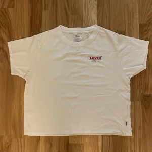 Vit t-shirt från Levi's med tryck - Vit t-shirt från Levi's med loga. Klassisk rund hals och korta ärmar, samt lite oversize. Mycket bra skick då den endast är använd fåtal gånger!