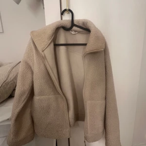 Beige teddyjacka - Mysig beige teddyjacka med dragkedja framtill och stora fickor. Perfekt nu till våren o sommaren!