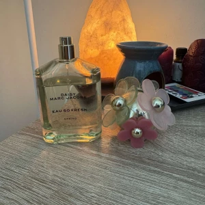 Daisy Eau So Fresh från Marc Jacobs - Charmig parfymflaska med blommig design från Marc Jacobs. Flaskan är grön med en unik kork dekorerad med rosa, beige och gröna blommor. Perfekt för den som älskar en fräsch och blommig doft. 