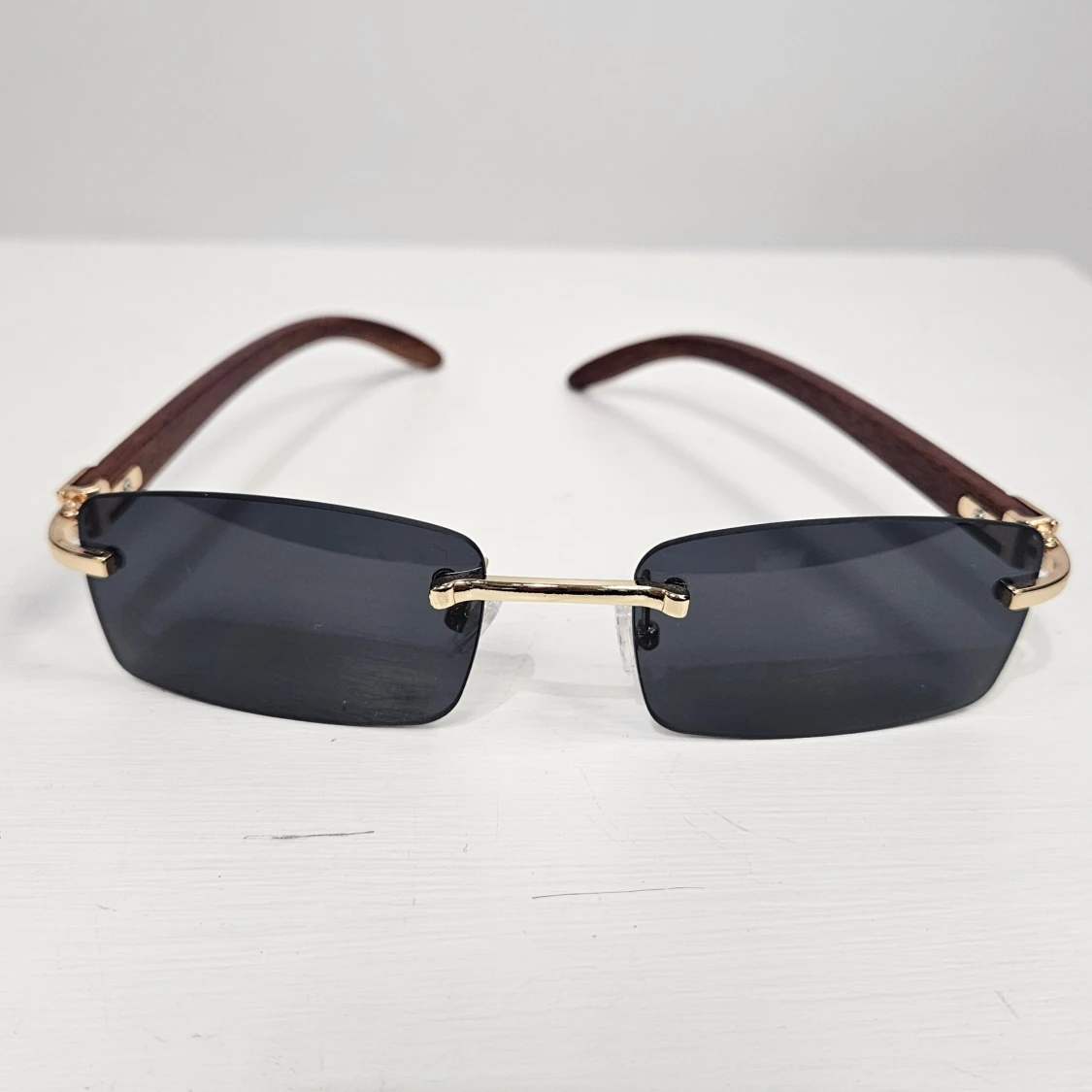 Svarta rektangulära solglasögon med gulddetaljer