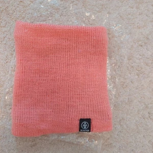 Rosa stickad halsduk från Winter - Mysig rosa halsduk i stickat material från Winter. Halsduken är tubformad och har en mjuk, fluffig insida som håller dig varm under kalla dagar. Perfekt accessoar för att addera färg till din vinteroutfit. Helt nu!