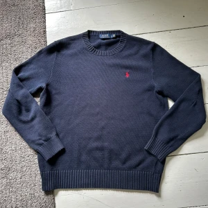 Marinblå Ralph Lauren Stickad Tröja - Stilren tröja från Ralph Lauren som passar perfekt till kyliga sommar/vårkvällar! | Mycket bra skick, enda defekten på tröjan är att på baksidan av armen på ena sidan så har materialet blivit tunnare, men det är inget man märker av! | Nypris: 2299kr | Priset är ej hugget i sten, och om det skulle finnas några funderingar är det bara och skriva! 😊