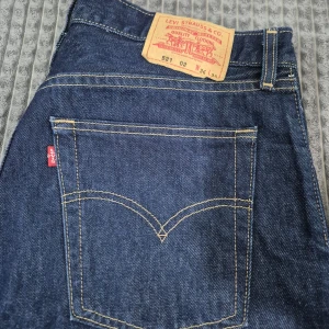 Levi's jeans  - Klassiska Levi's 527 jeans i mörkblå denim med raka ben och femficksmodell. Byxorna har tydliga kontrastsömmar, läderpatch bak och den ikoniska röda Levi's-taggen på bakfickan. Perfekta för dig som gillar tidlös jeansstil.