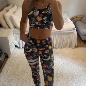 Färgglada träningsbyxor från Stronger - Säljer träningsbyxor från Stronger med färgglatt fruktmönster på mörkblå botten. Är helt oanvända så är helt nya! Köpta för 899 kr!